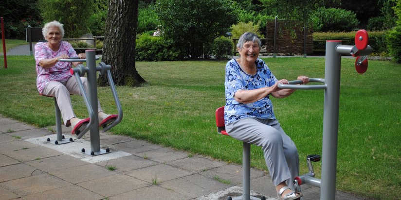 Bewohnerinnen nutzen die Sportgeräte im Garten 