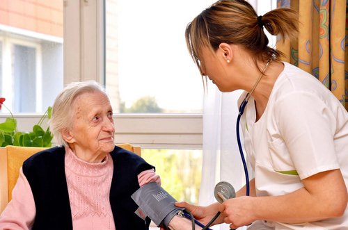 Eine Mitarbeiterin misst den Blutdruck bei einer älteren Dame.