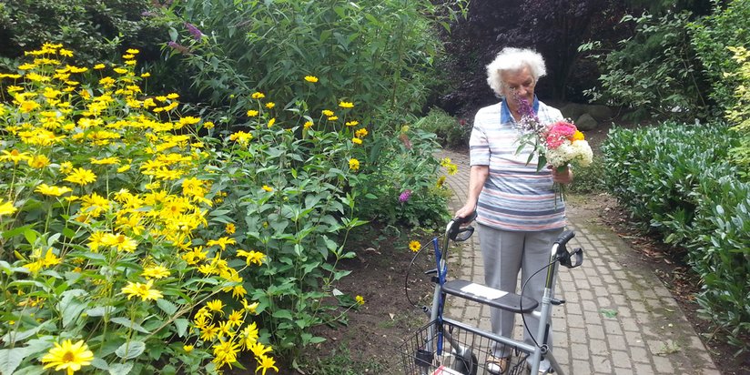Eine ältere Dame genießt einen Spaziergang im Garten 